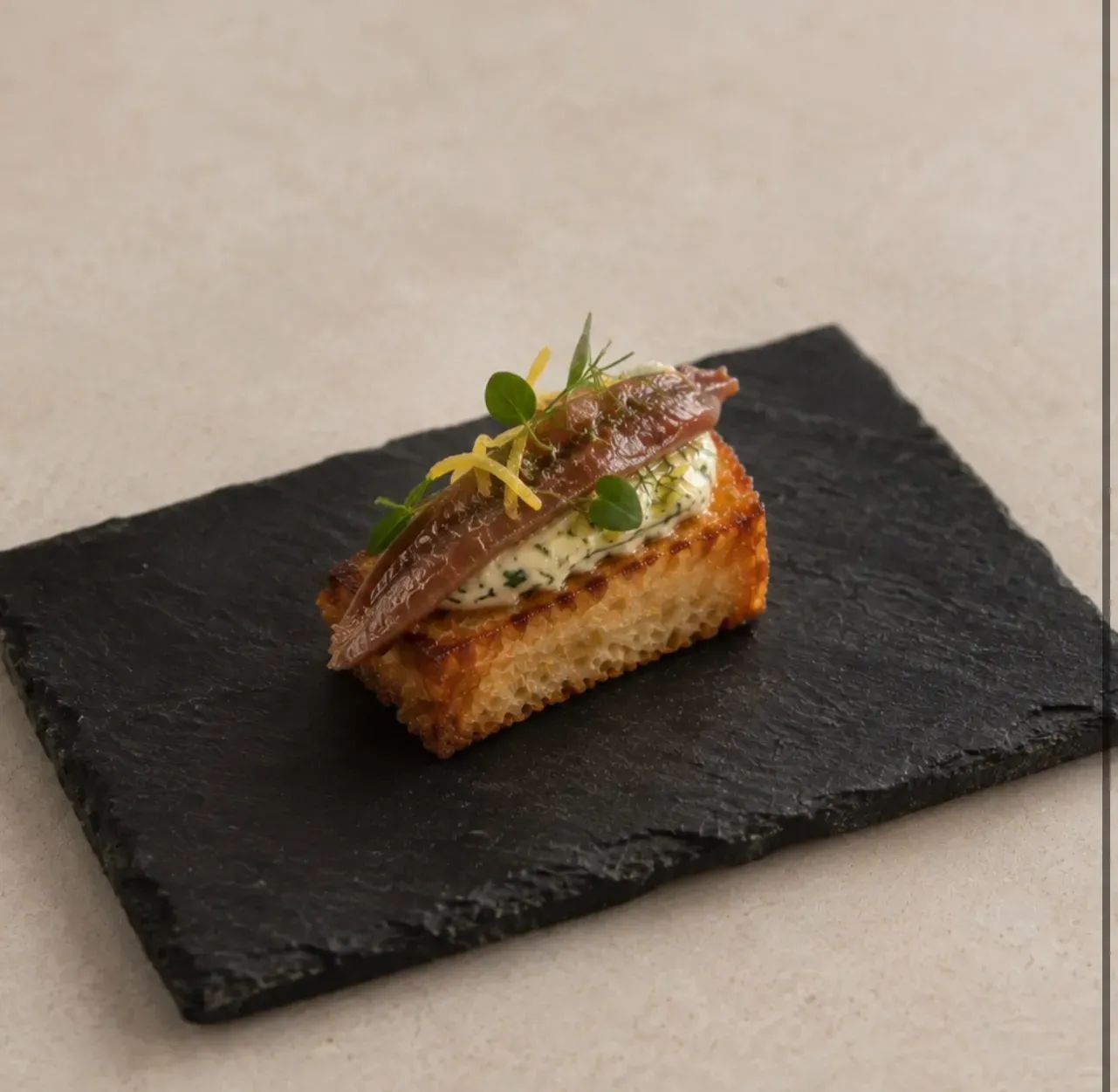 Brioche tostado, mantequilla de hierbas y anchoa.