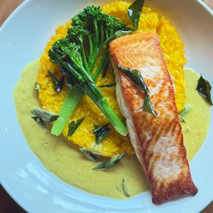 salmon over crispy saffron risotto and curry sauce a an